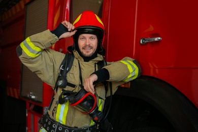 Photo of Portrait of firefighter in uniform near red fire truck at station