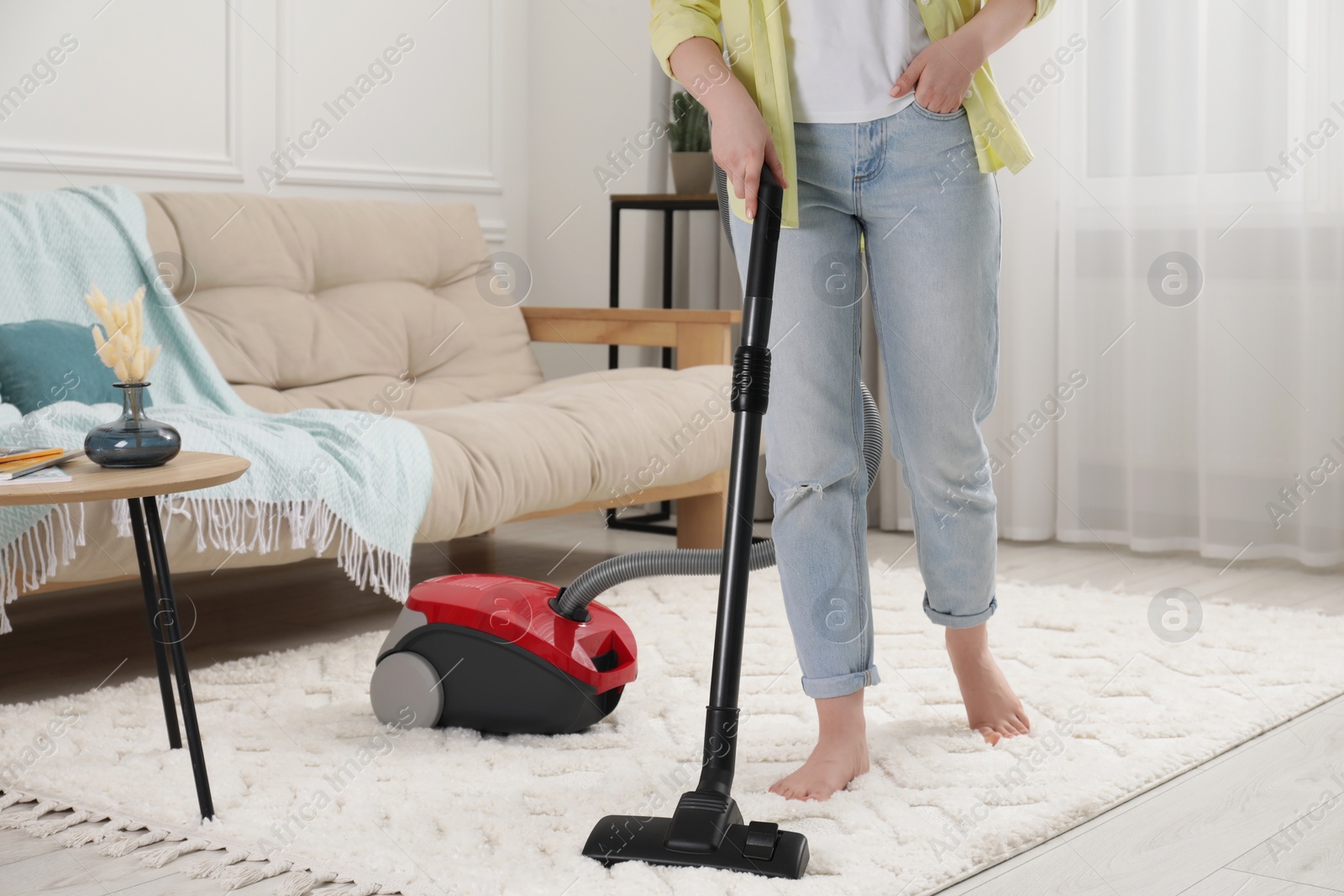 Photo of Woman cleaning carpet with vacuum cleaner at home, closeup