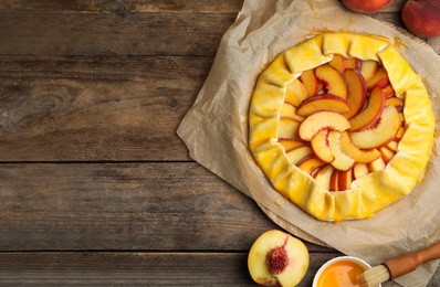 Flat lay composition with uncooked peach pie on wooden table. Space for text