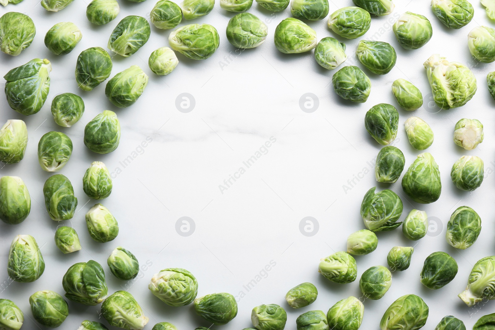 Photo of Frame of Brussels sprouts on white marble table, flat lay. Space for text