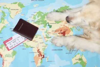 Photo of Golden retriever lying near passport and ticket on world map, top view. Travelling with pet