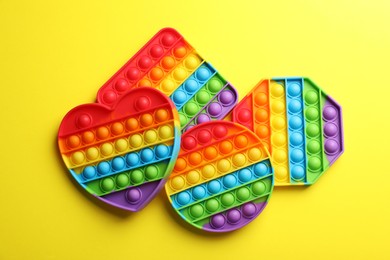 Photo of Many different rainbow pop it fidget toys on yellow background, flat lay