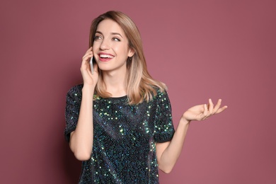 Young woman talking on phone against color background