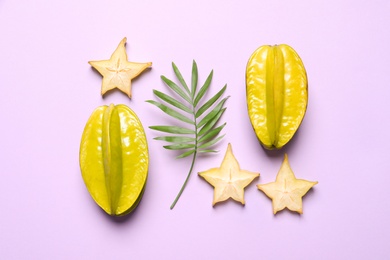 Delicious carambola fruits on violet background, flat lay