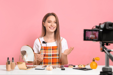 Beauty blogger filming make up tutorial on pink background