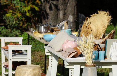 Small tables with many different items on garage sale outdoors