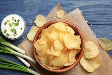 Photo of Flat lay composition with potato chips and sauce on wooden table