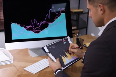 Photo of Businessman working with computer and graph in office, closeup. Forex trading