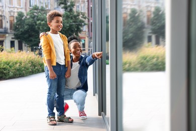 Happy mother pointing at window and her son outdoors