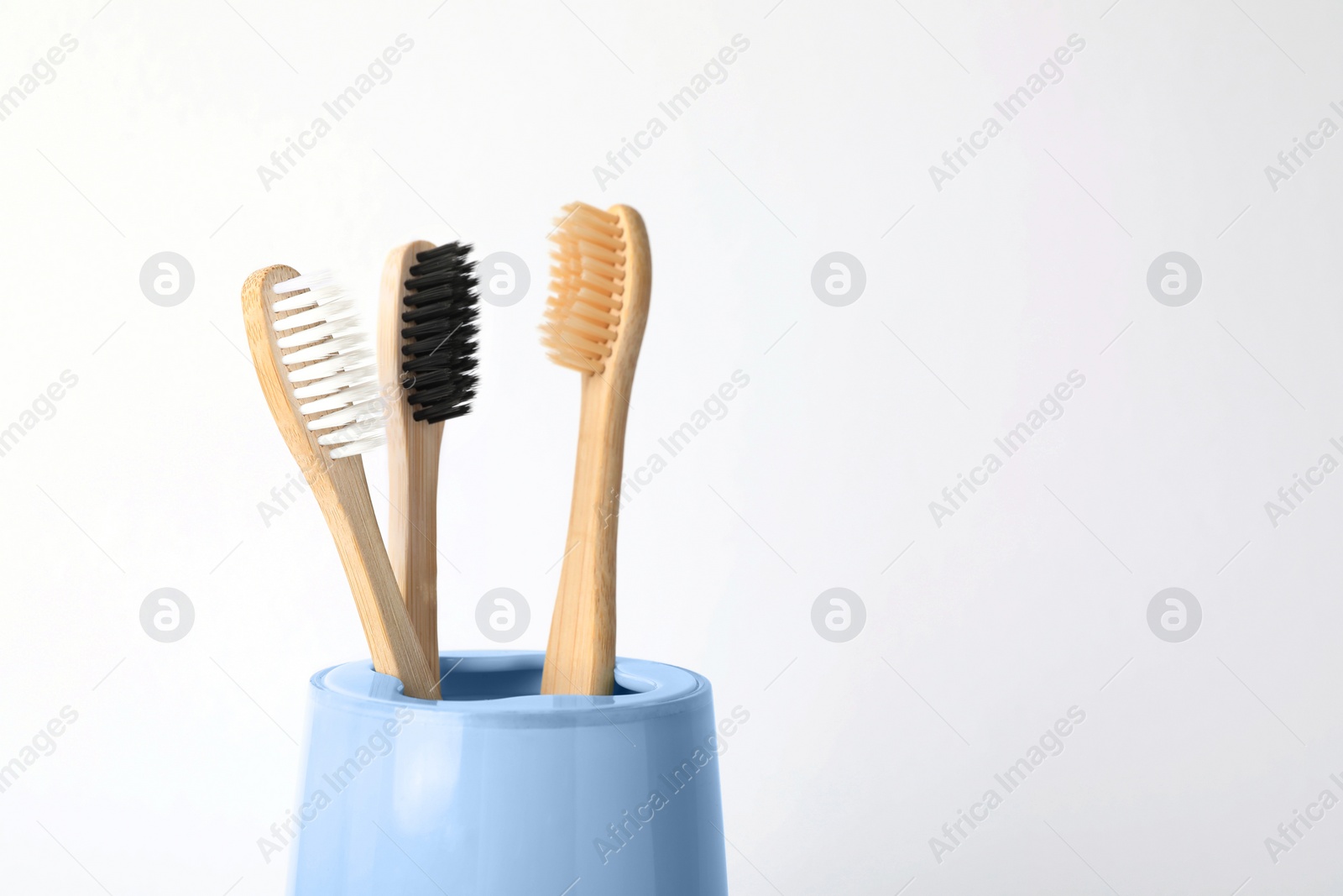 Photo of Bamboo toothbrushes in holder on white background, space for text