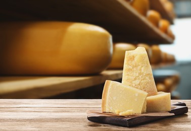 Delicious parmesan cheese on wooden table in warehouse, space for text