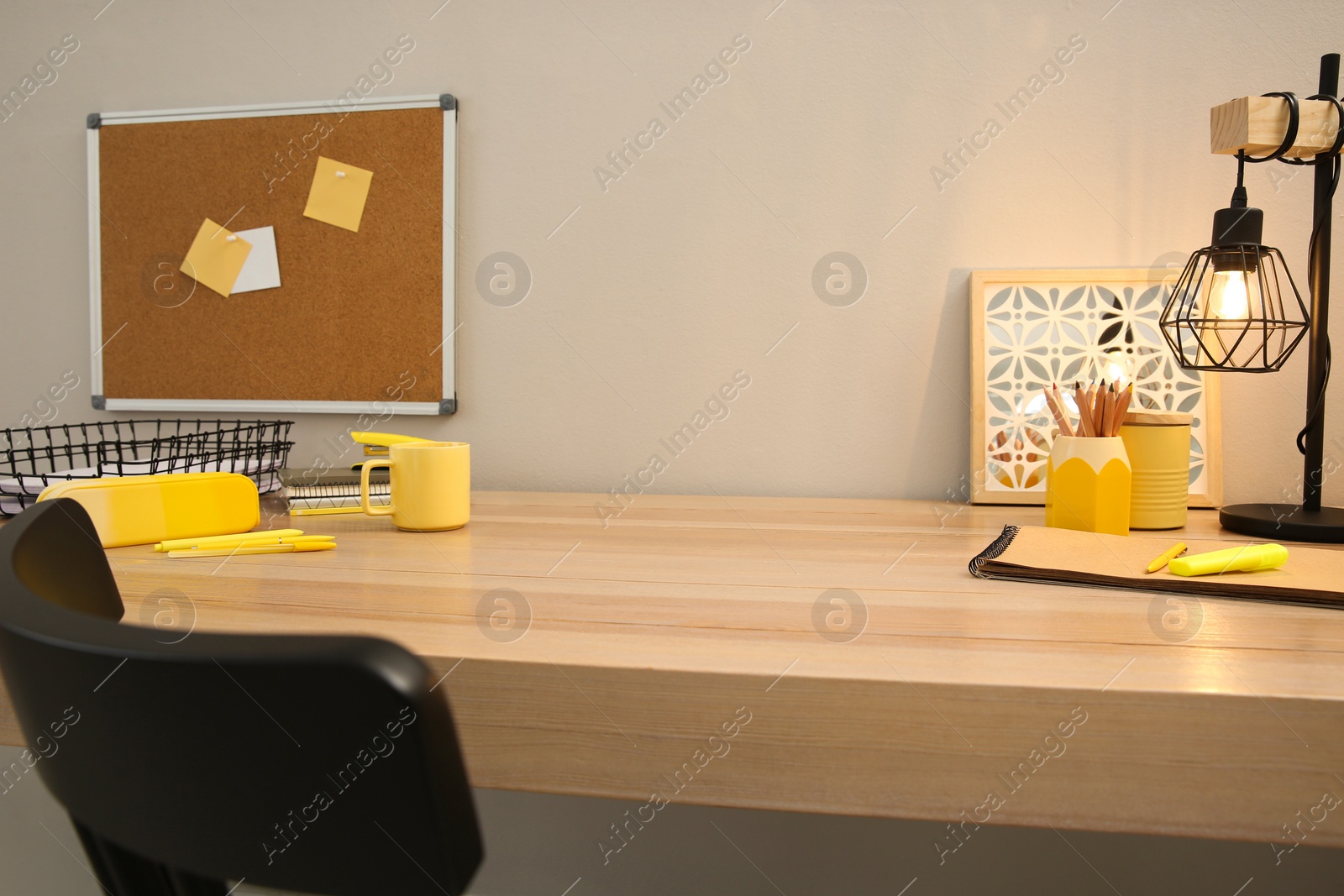 Photo of Stylish workplace with stationery on wooden desk near light wall. Interior design