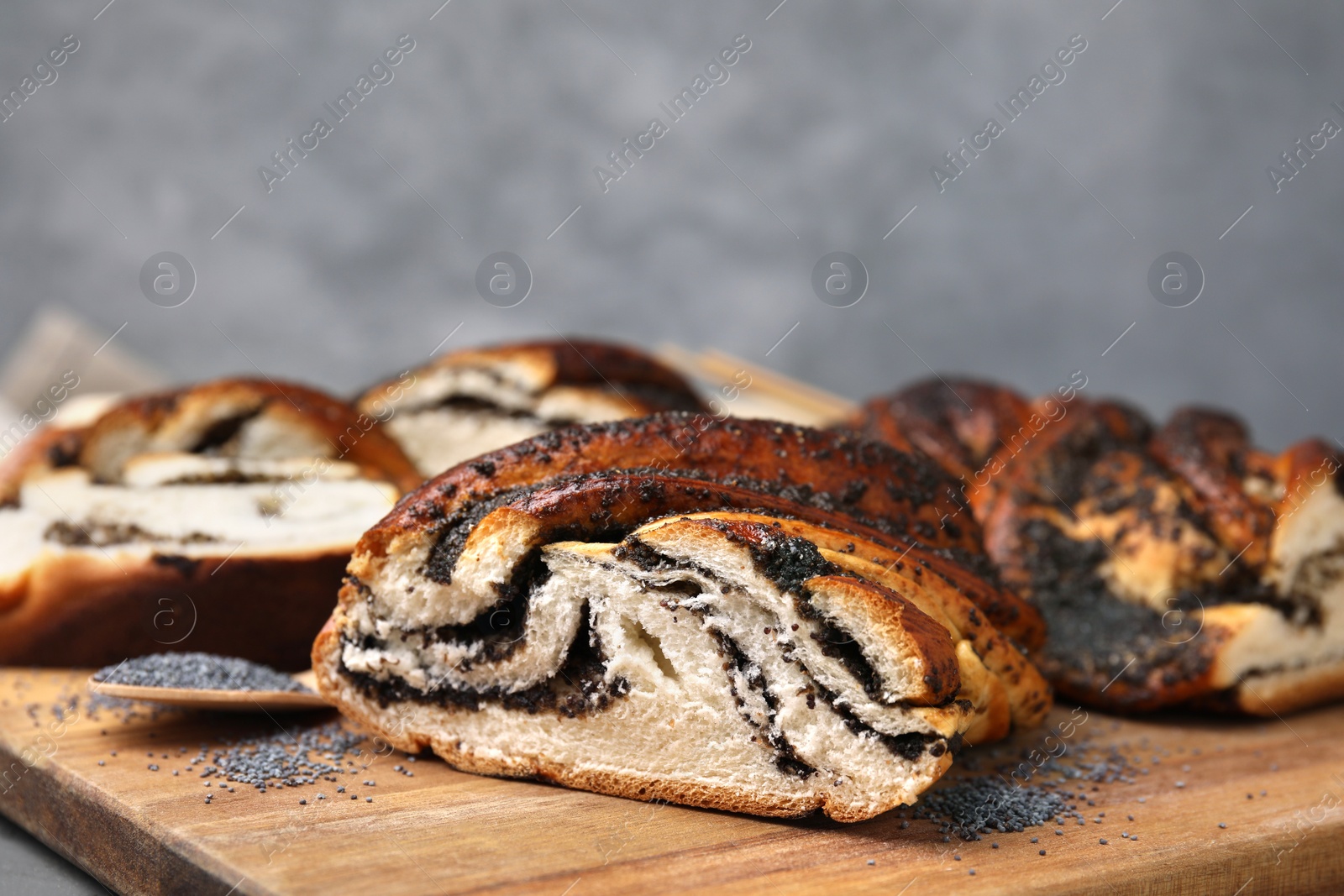 Photo of Cut poppy seed roll on wooden board, closeup. Tasty cake