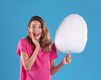 Photo of Emotional woman with cotton candy on blue background