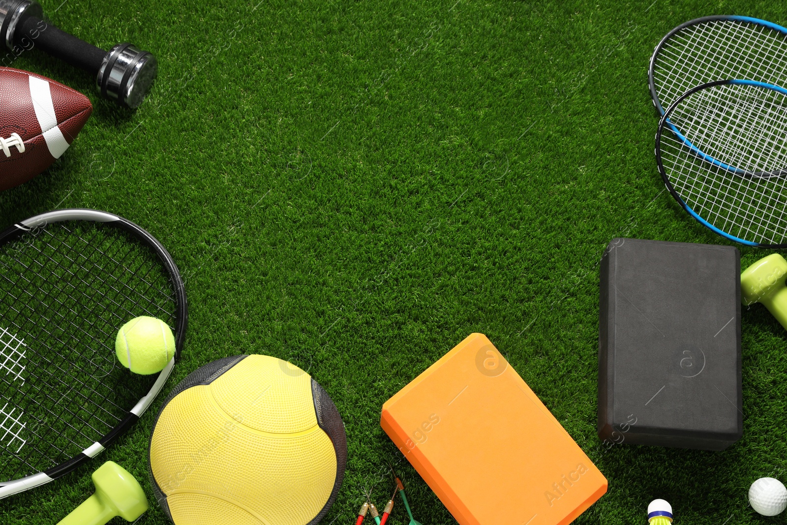 Photo of Different sports equipment on green grass, flat lay. Space for text