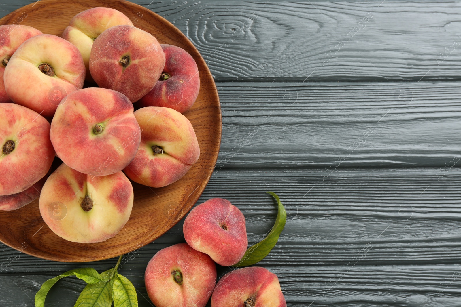 Photo of Fresh ripe donut peaches on grey wooden table, flat lay. Space for text