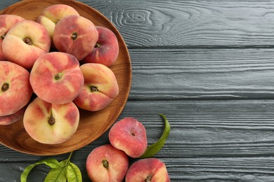 Fresh ripe donut peaches on grey wooden table, flat lay. Space for text