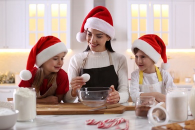 Mother with her cute little children making Christmas cookies in kitchen