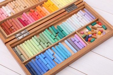Photo of Set of soft pastels in box on white wooden table. Drawing material