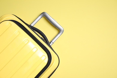 Photo of Modern suitcase on yellow background, top view