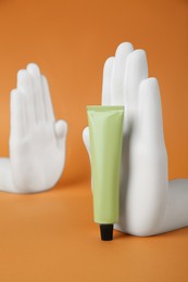 Photo of Composition with tube of hand cream on orange background