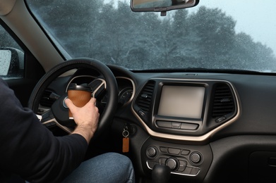 Young man with coffee inside car, closeup