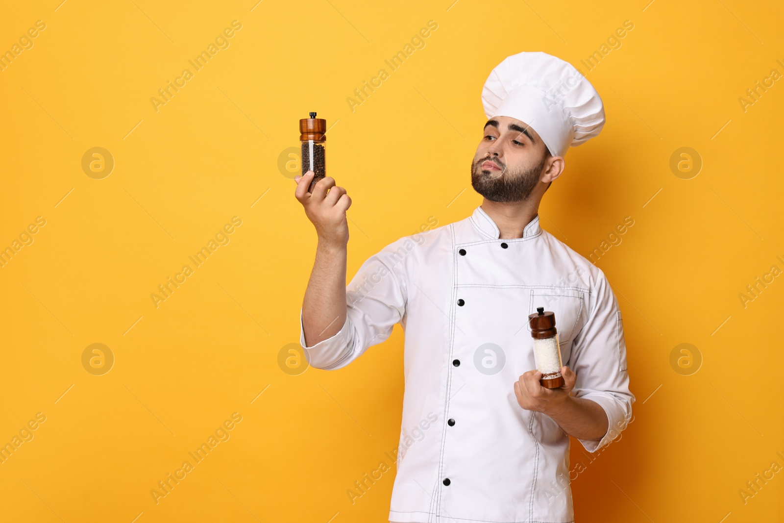 Photo of Professional chef with shakers on yellow background. Space for text