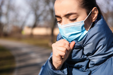 Photo of Woman wearing disposable mask outdoors, closeup. Dangerous virus