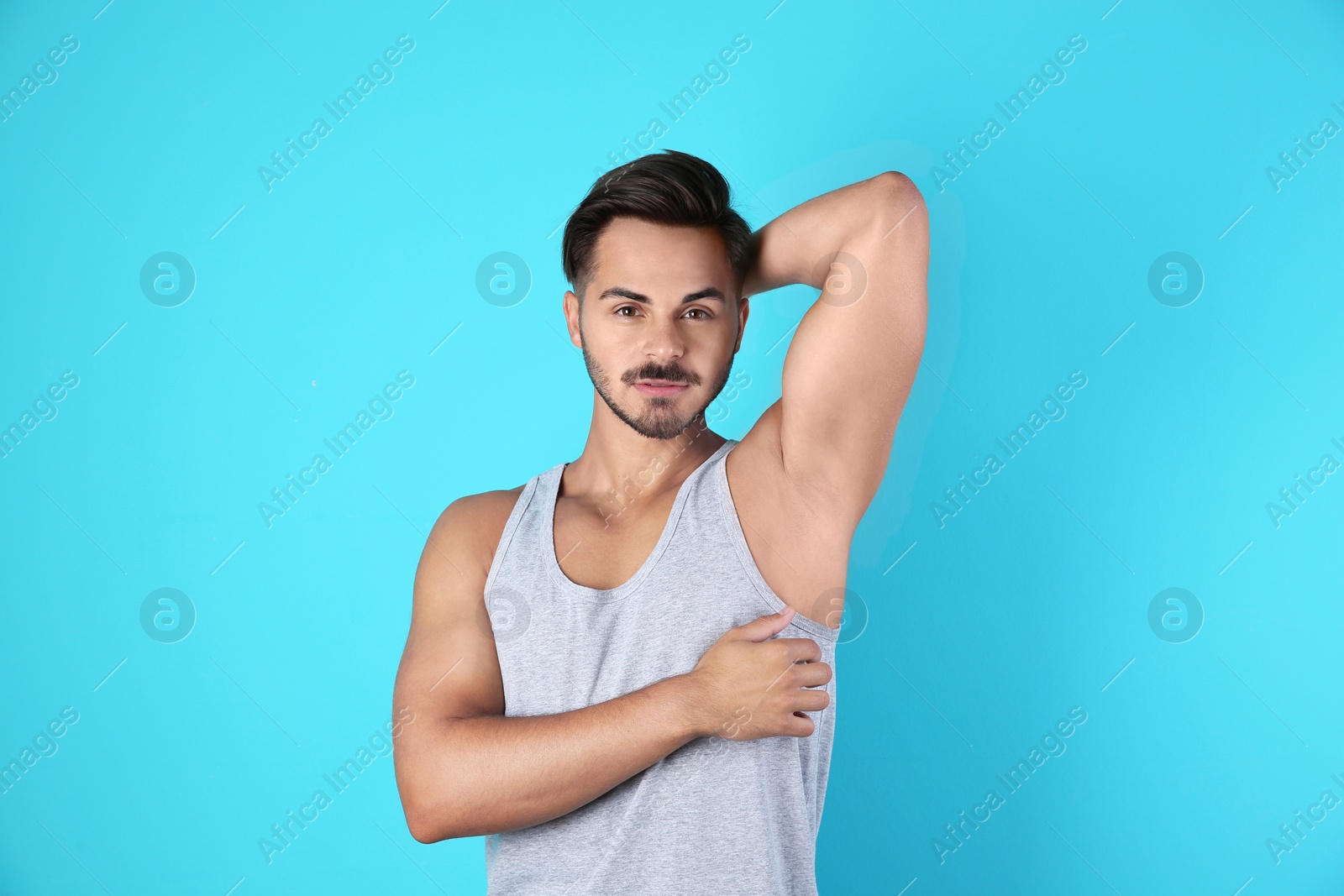 Photo of Handsome young man showing armpit on color background. Using deodorant