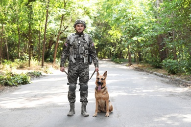 Man in military uniform with German shepherd dog outdoors