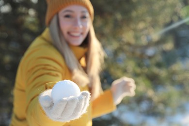 Photo of Woman with snowball outdoors, focus on hand. Space for text