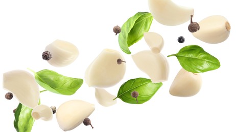 Image of Fresh peeled garlic cloves, peppercorns and basil leaves flying on white background