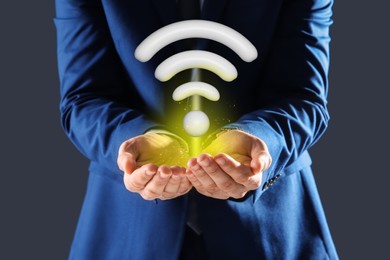 Image of Man holding Wi Fi symbol in hands on dark grey background, closeup