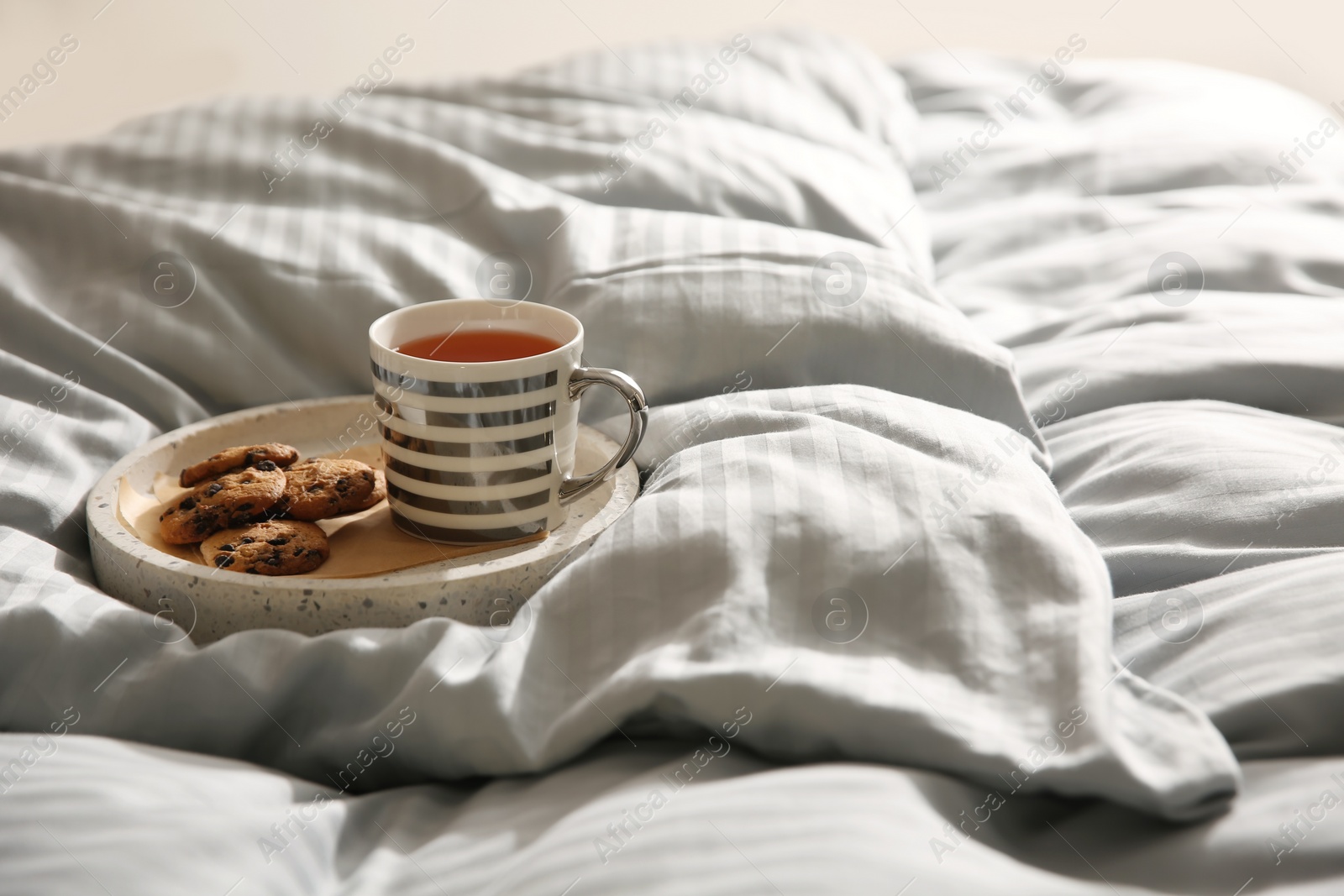 Photo of Tray with cup of tea and cookies on soft blanket. Space for text