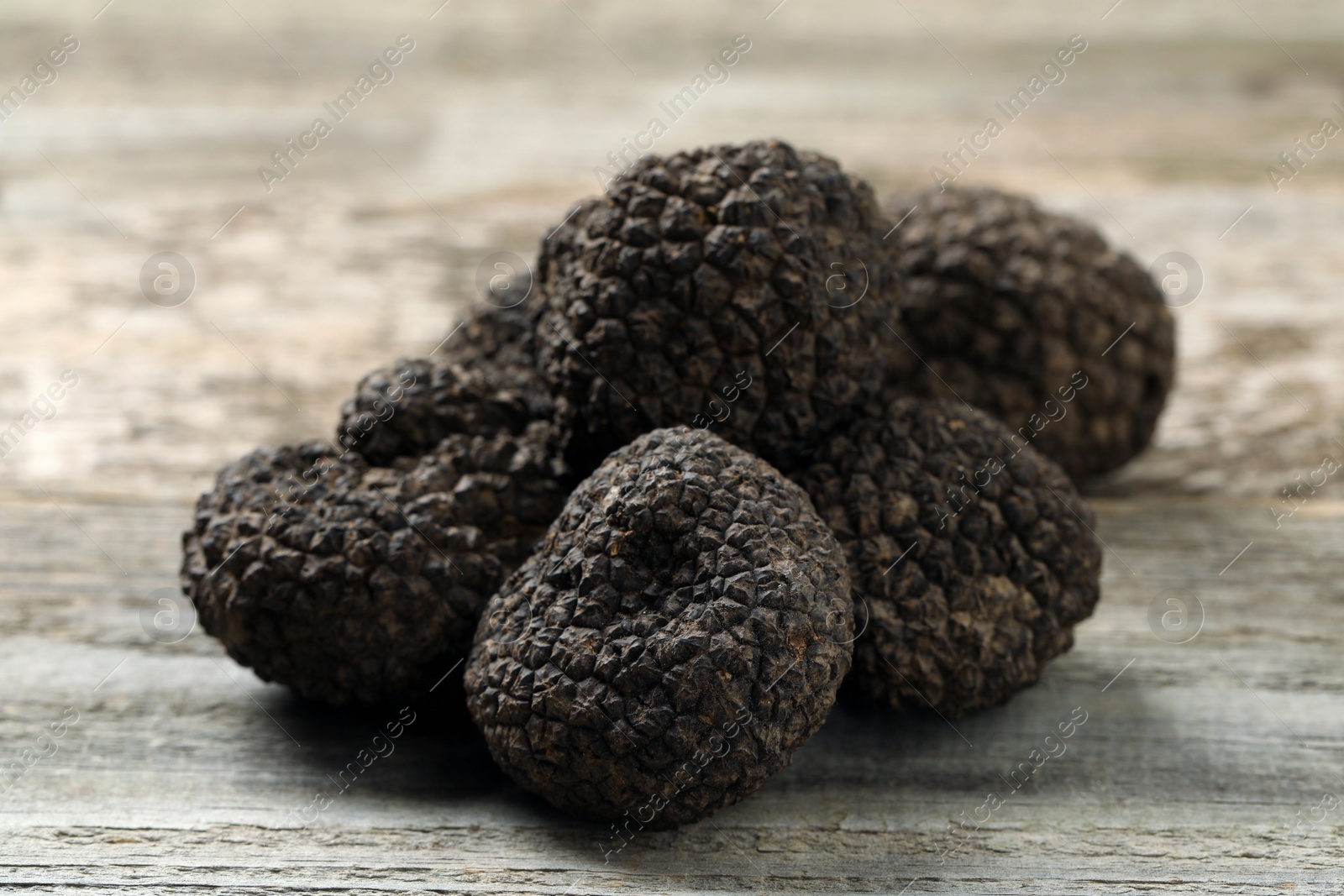 Photo of Heap of black truffles on wooden table, closeup