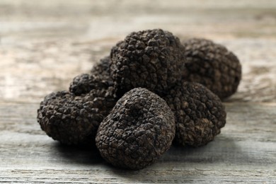 Photo of Heap of black truffles on wooden table, closeup