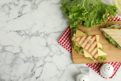 Photo of Wooden board with tasty sandwiches on white marble table, flat lay. Space for text