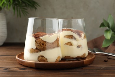 Delicious tiramisu in glasses on wooden table, closeup