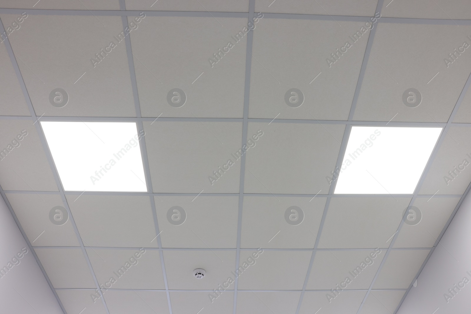 Photo of White ceiling with PVC tiles and lighting indoors, low angle view