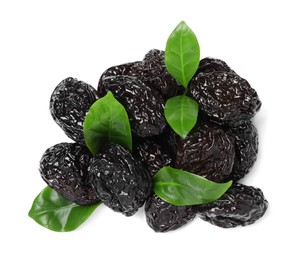 Photo of Heap of sweet dried prunes and green leaves on white background, top view