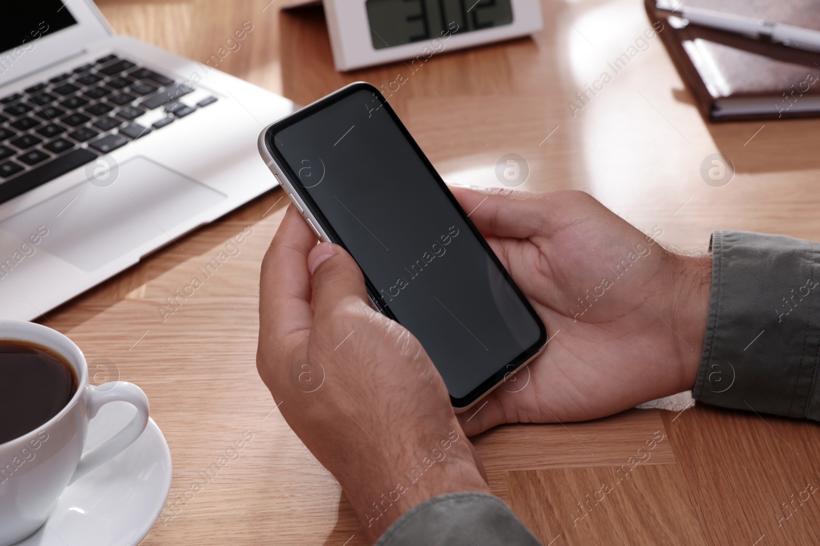 Photo of Man holding mobile phone with empty screen at table, closeup