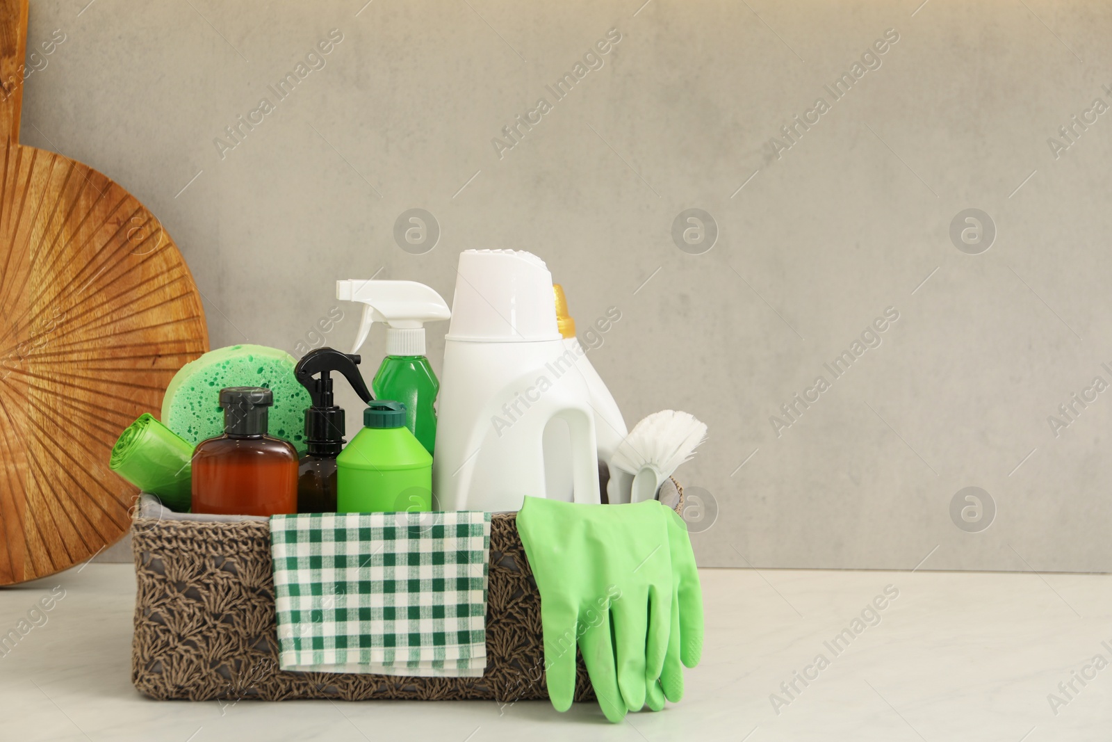 Photo of Different cleaning supplies in basket on countertop. Space for text