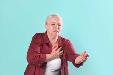 Photo of Mature woman having heart attack on color background