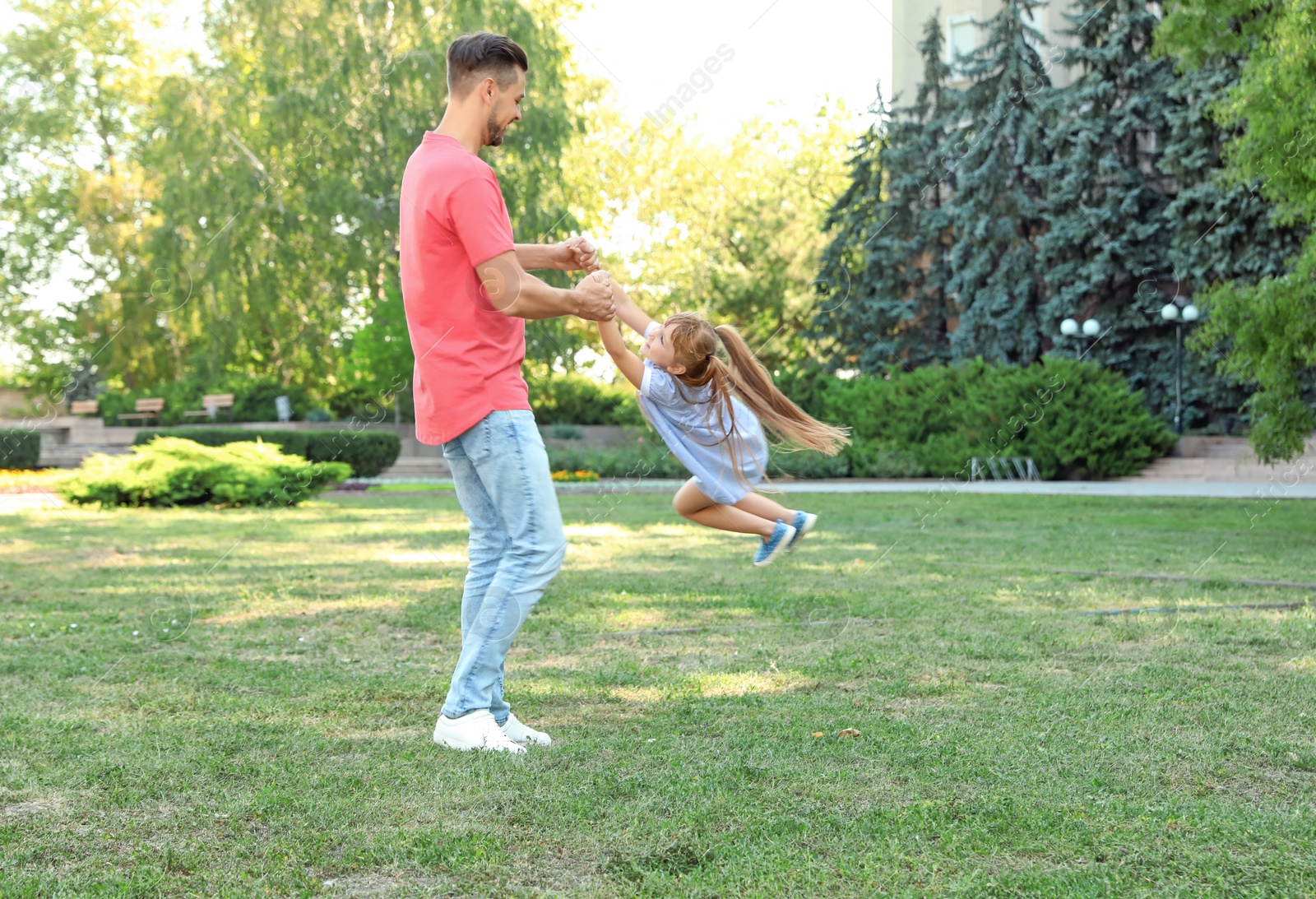 Photo of Father having fun with his cute child in green park on sunny day. Happy family