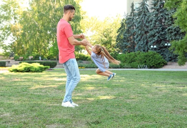 Father having fun with his cute child in green park on sunny day. Happy family