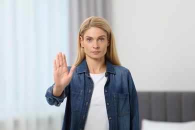 Photo of Woman showing stop gesture in light room
