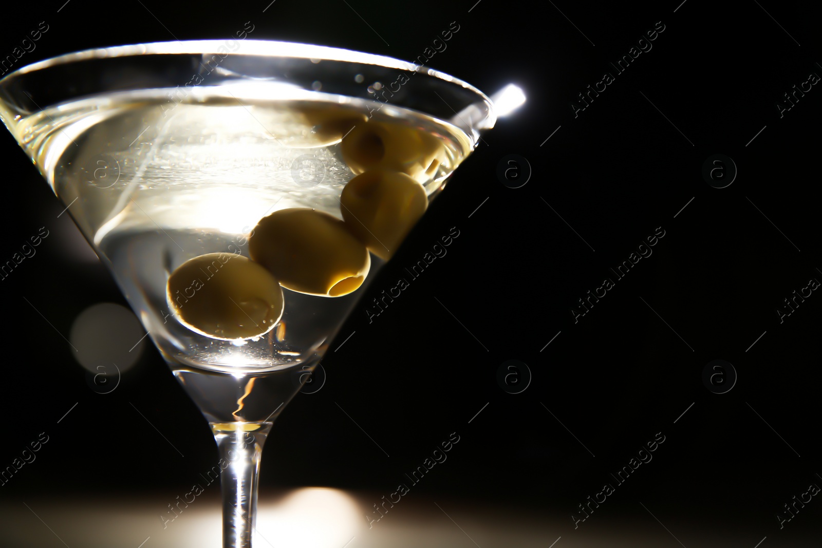 Photo of Glass of martini with olives in bar, closeup. Space for text
