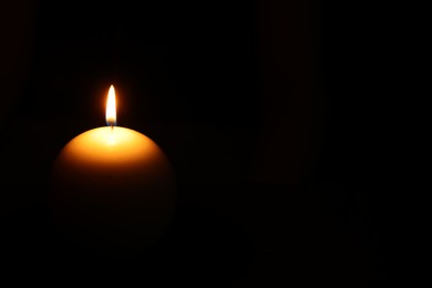 One round burning candle on black background, space for text
