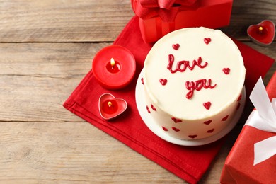 Photo of Bento cake with text Love You, candles and gift boxes on wooden table, space for text. St. Valentine's day surprise