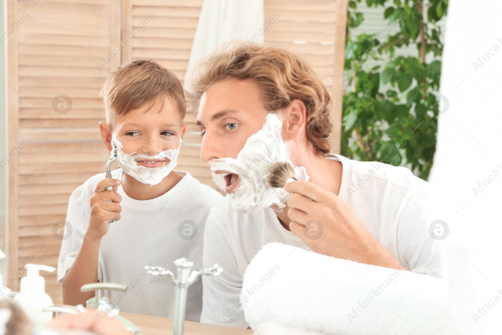 Photo of Father and son shaving together in bathroom